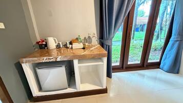 A kitchen counter with a coffee maker, cups, and a trash bin.