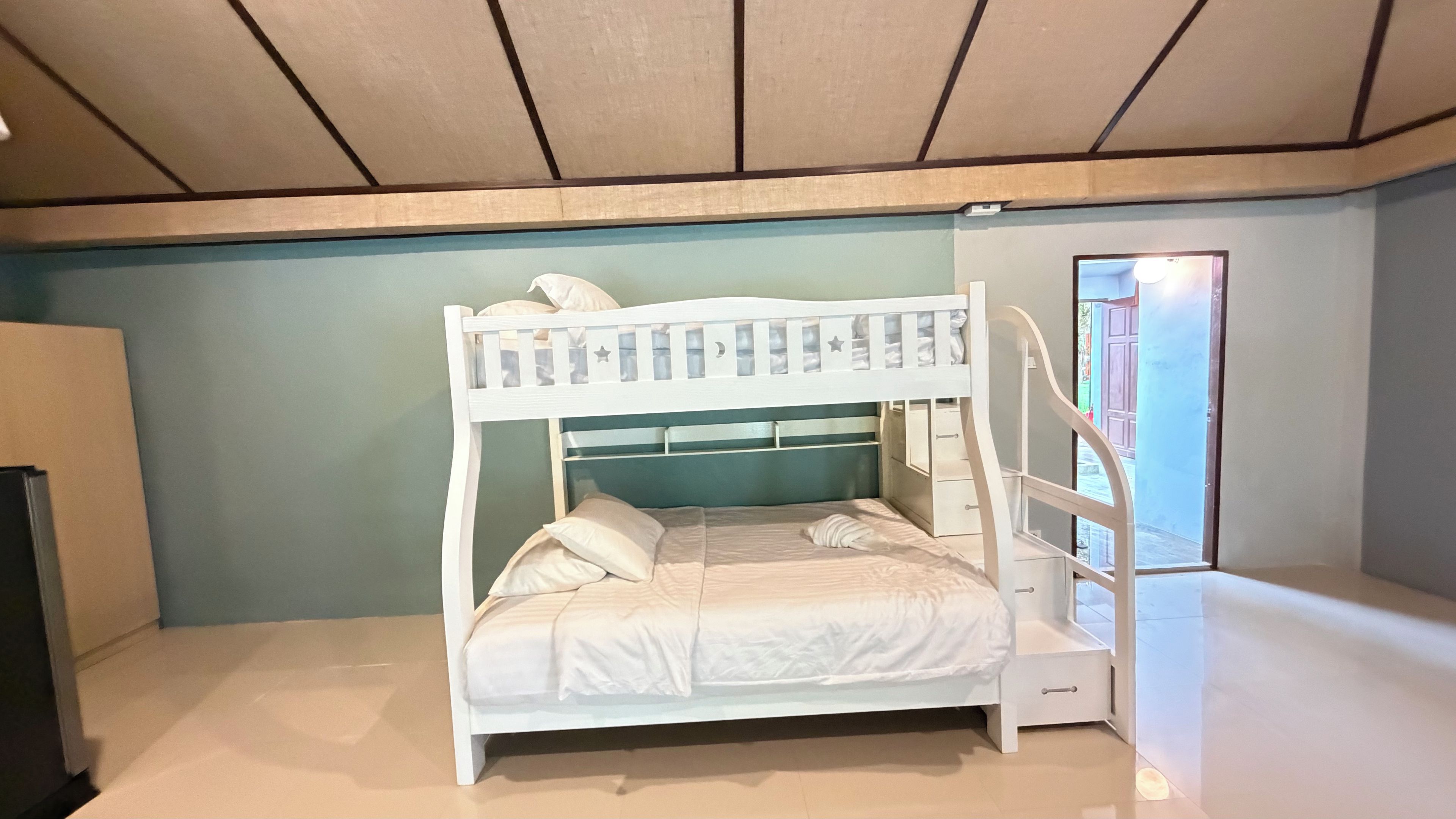 A bunk bed with a headboard featuring a moon and stars design, a bedside table, and a window with a view of the outside.