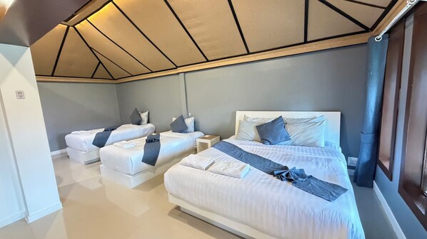 Habitación de hotel con dos camas, un ventanal grande y un techo con diseños geométricos.
