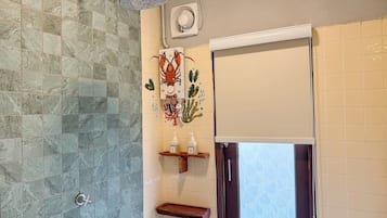 A bathroom with a shower, a toilet, and a sink with a decorative coral mural.