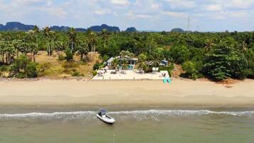 A beach with a house and palm trees in the background.