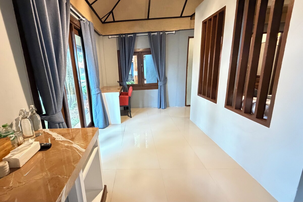A corridor with a marble counter, a red chair, and a window with curtains.