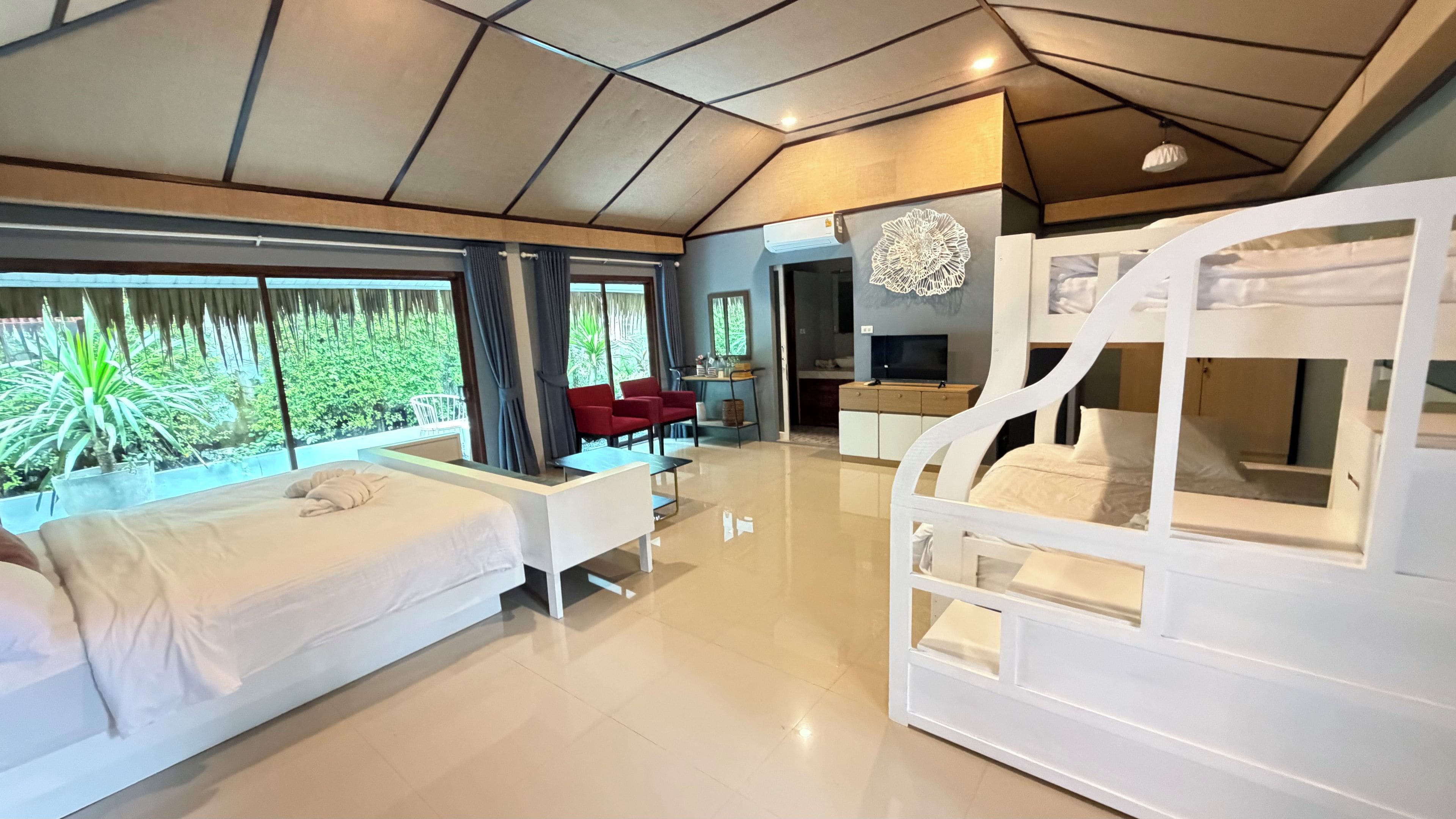 Una habitación de hotel moderna con literas, un escritorio, una silla y un televisor.