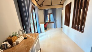 A hotel corridor with a marble counter, a red chair, and a view of a garden through the window.