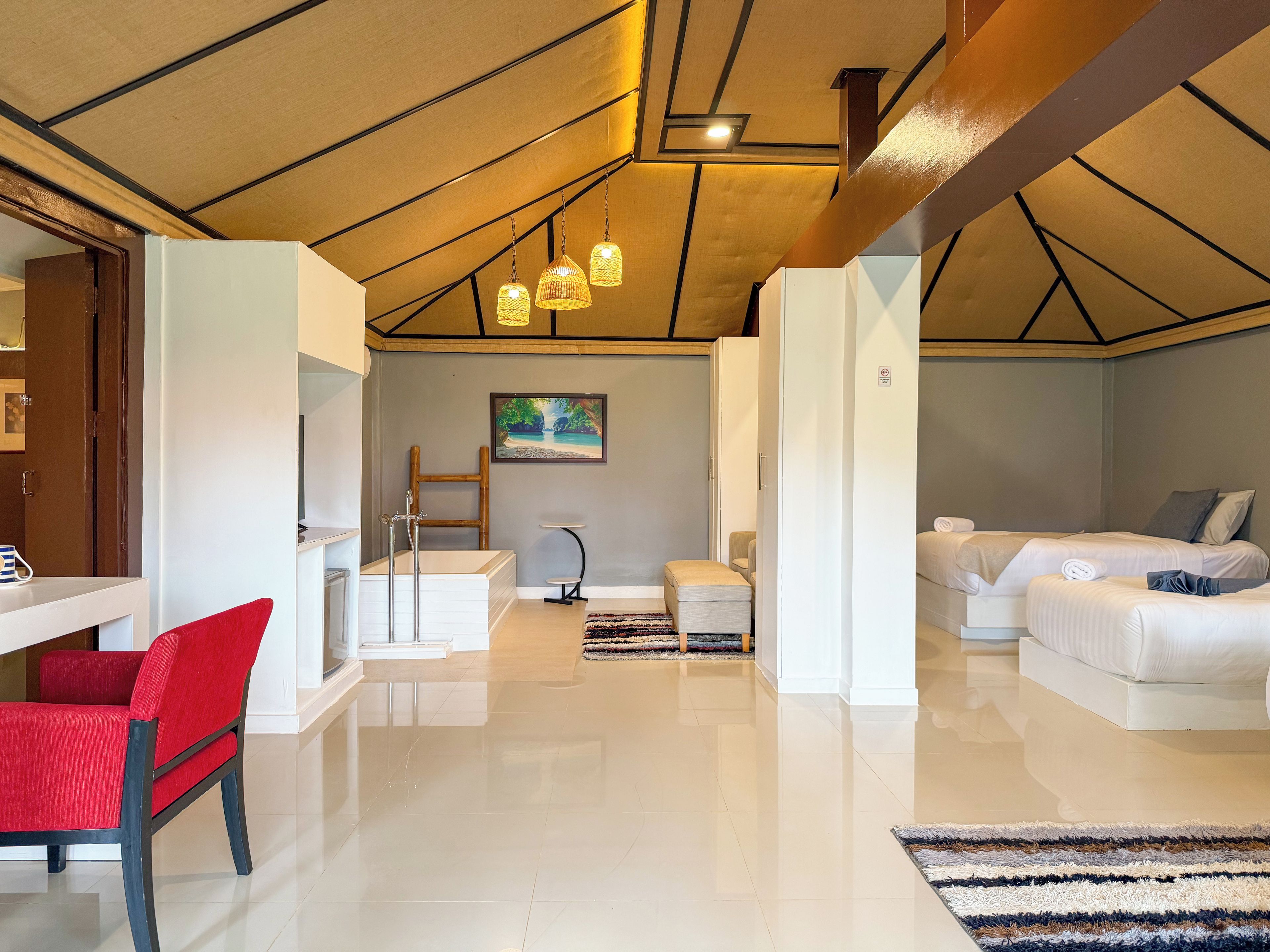 Un interior moderno con un sofá blanco, una silla roja, una mesita y un cuadro en la pared.