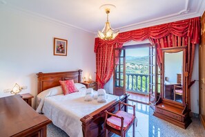 Ein Schlafzimmer mit Bett, Nachttisch, Lampe und Blick ins Freie.