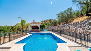 A swimming pool with a stone wall and a building with a tiled roof in the background. - Cubo's Paraje Galiano Rural House / Private pool / BBQ / Free Wi-Fi (Guaro)