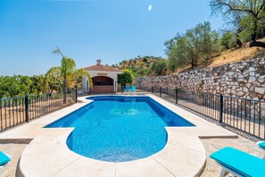 A swimming pool with a stone wall and a building with a tiled roof in the background. - Cubo's Paraje Galiano Rural House / Private pool / BBQ / Free Wi-Fi (Guaro)