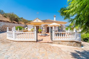 Eine traditionelle Villa im mediterranen Stil mit einer Stein-Fassade, einem Ziegeldach und einem umzäunten Innenhof.