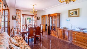 A well-lit dining area with a chandelier, wooden furniture, and a view through a glass door. - Cubo's Paraje Galiano Rural House / Private pool / BBQ / Free Wi-Fi (Guaro)