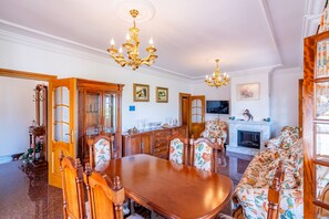 Een eetkamer met een houten tafel en stoelen, een kroonluchter en een open haard.