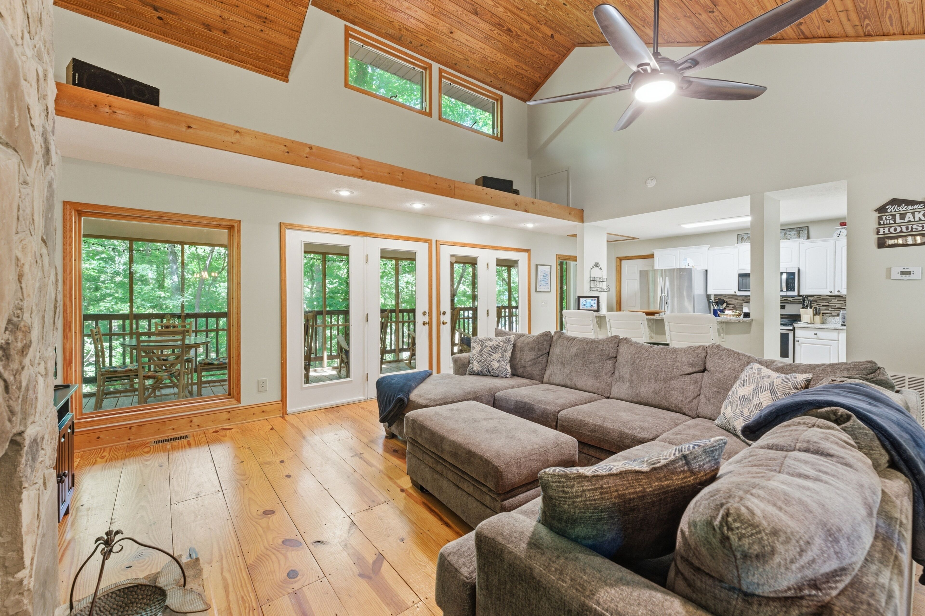 A spacious living room with a large sectional sofa, wooden flooring, and a ceiling fan.