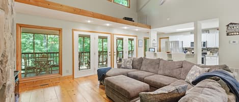 A spacious living room with a large sectional sofa, wooden flooring, and a ceiling fan.