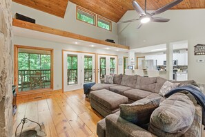 A spacious living room with a large sectional sofa, wooden flooring, and a ceiling fan. - Lake Hartwell Retreat w/Dock & Lake Access, Foosball, Ping Pong, Mini Golf & BBQ (Lavonia)