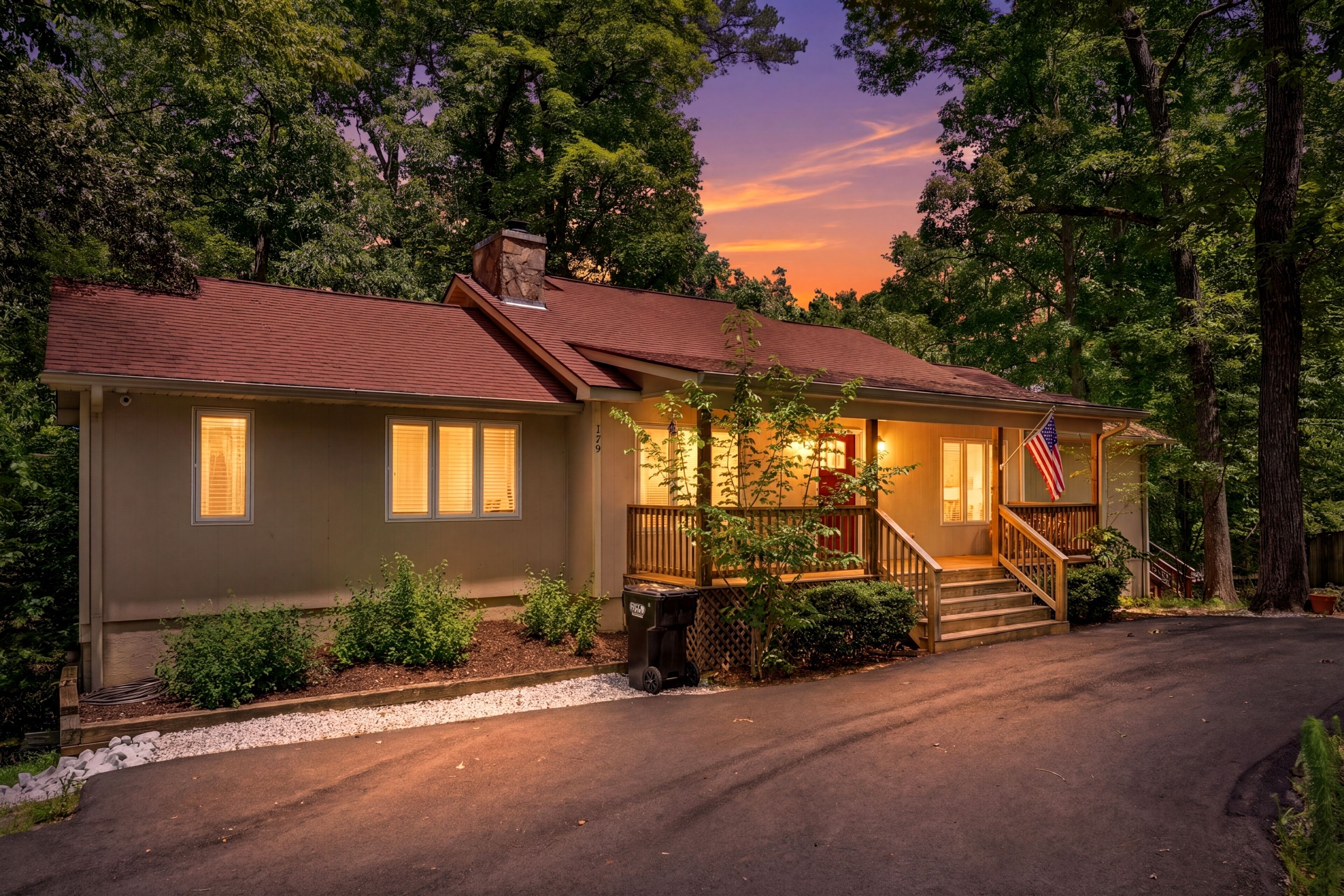 Een tweelaags huis met een veranda, schoorsteen en een Amerikaanse vlag.