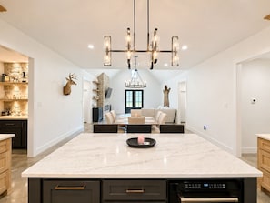 A spacious kitchen with a large island, modern appliances, and a chandelier.