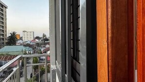 Ein Balkon mit Blick auf eine Stadtlandschaft, darunter Gebäude und ein klarer Himmel.