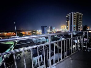 A nighttime cityscape with buildings, a metal railing, and a parking area. - Tarans Homes (Dar es Salaam)