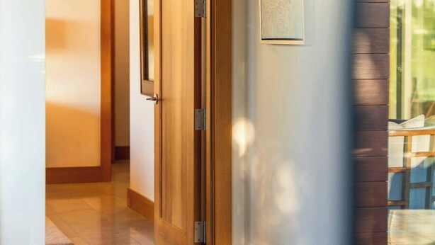 Un pasillo con una puerta de madera, un cuadro en la pared y vistas del exterior a través de una ventana.