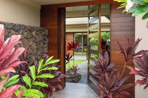 A modern interior with a stone wall, wooden paneling, and tropical plants. - Mauna Lani Villa | Pool, Spa, Golf Views, Beach Club & Golf Cart Included (Waimea)