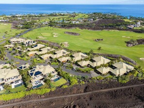 A golf course with a residential area featuring modern houses with solar panels, surrounded by lush greenery and a clear view of the ocean. - Mauna Lani Villa | Pool, Spa, Golf Views, Beach Club & Golf Cart Included (Waimea)