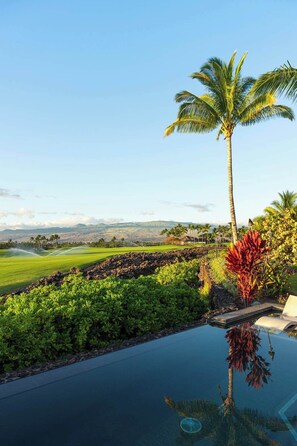 Ein Pool mit freiem Blick auf einen Golfplatz und ein Gebirge in der Ferne.