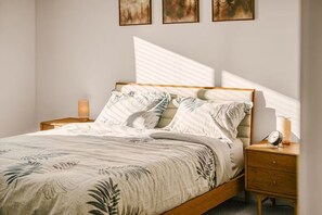 A bedroom with a bed, nightstands, a lamp, and wall art. - Scandinavian 4BR - King Suite · EV Plug · Sleeps 10 (Gresham)