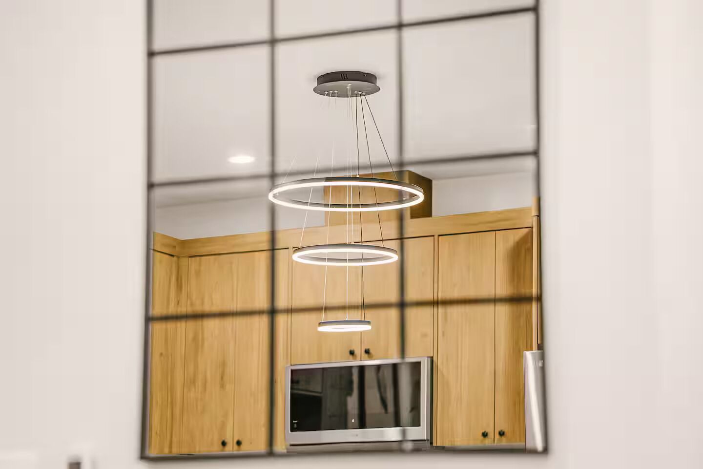 A modern kitchen with wooden cabinets, a built-in microwave, and a pendant light fixture.
