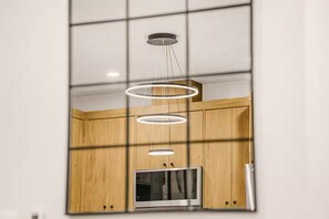 Una cocina moderna con armarios de madera, microondas integrado y una lámpara colgante.