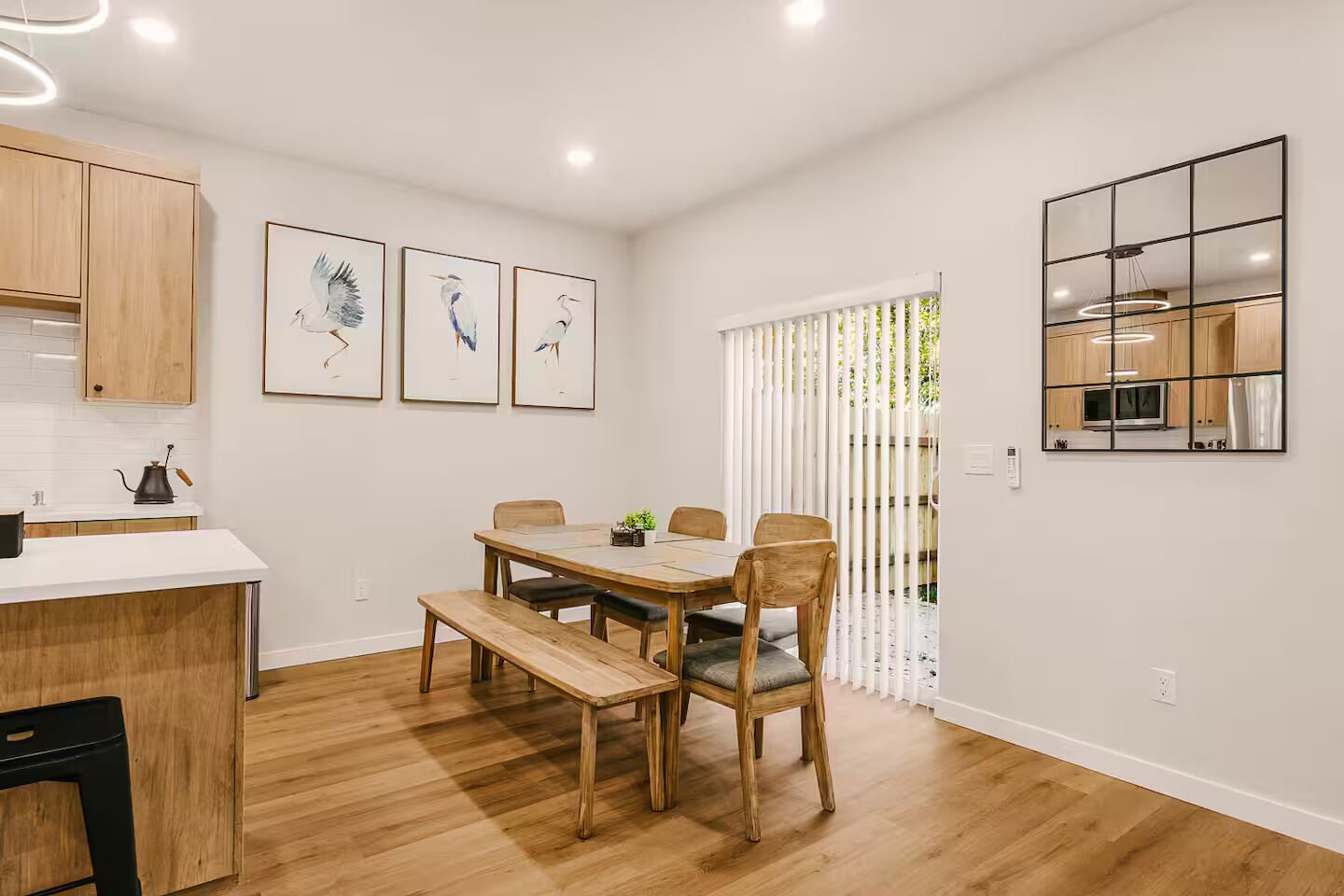A dining area with a wooden table and chairs, a bench, and framed artwork on the wall.