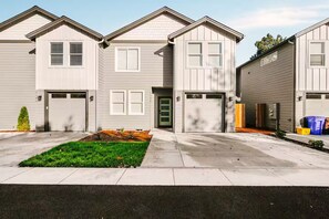 A row of townhouses with attached garages, a well-maintained lawn, and a clear sky. - Scandinavian 4BR - King Suite · EV Plug · Sleeps 10 (Gresham)