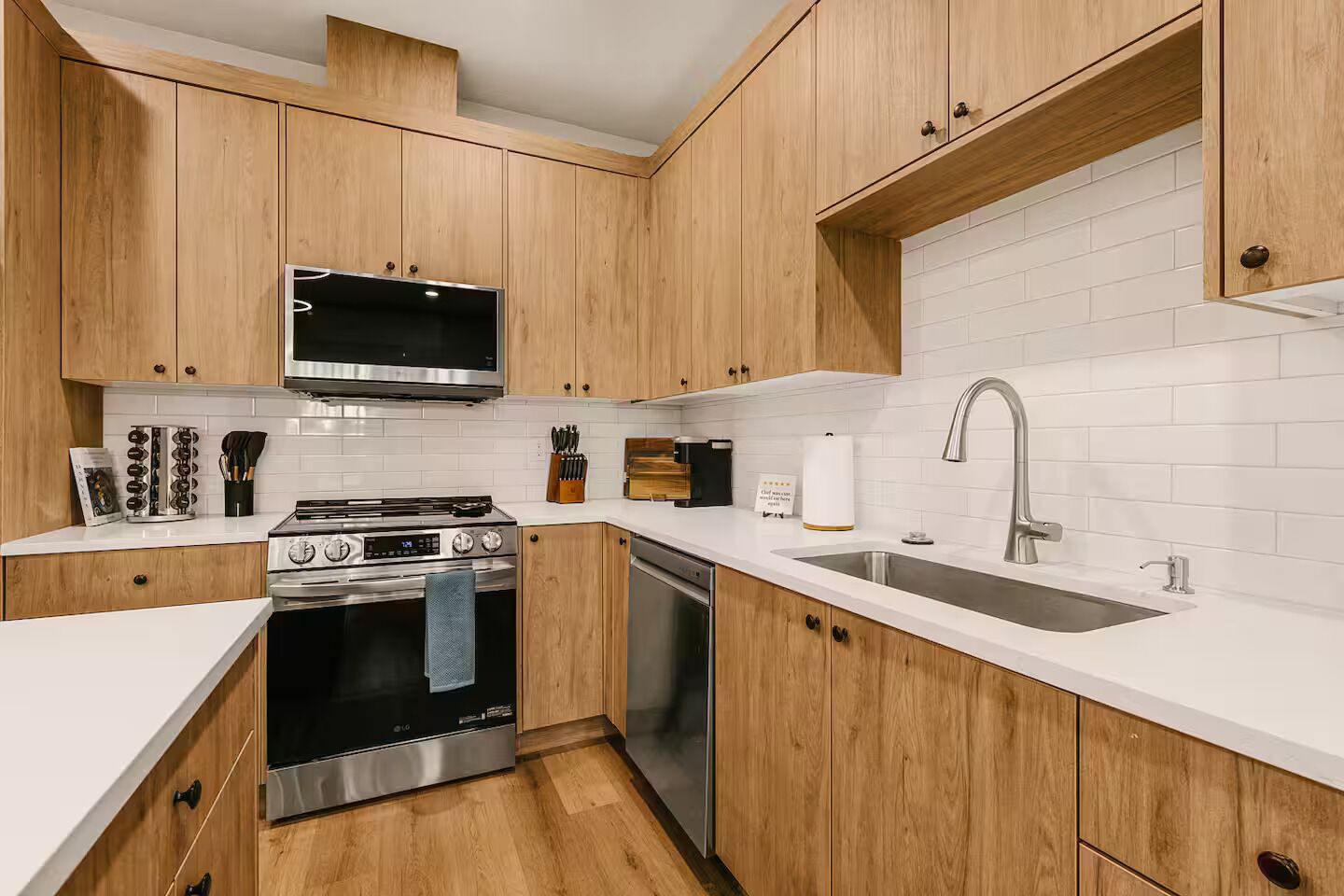 Una cocina moderna con armarios de madera, electrodomésticos de acero inoxidable y salpicadero de azulejos blancos.