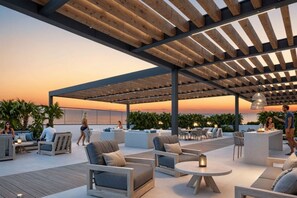 An outdoor patio area with wooden pergolas, seating arrangements, and a view of the ocean at sunset. - VITA 219 Apartment - Near the Sea by SOHO - 388A (Santa Marta)