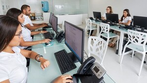 Ein modernes Büro mit Glastrennwänden, weißen Möbeln und mehreren Computerarbeitsplätzen.