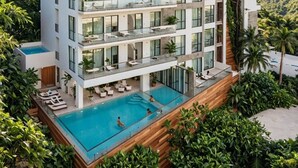 Ein mehrstöckiges Hotel mit Balkonen, einem Schwimmbad und üppiger Bepflanzung.