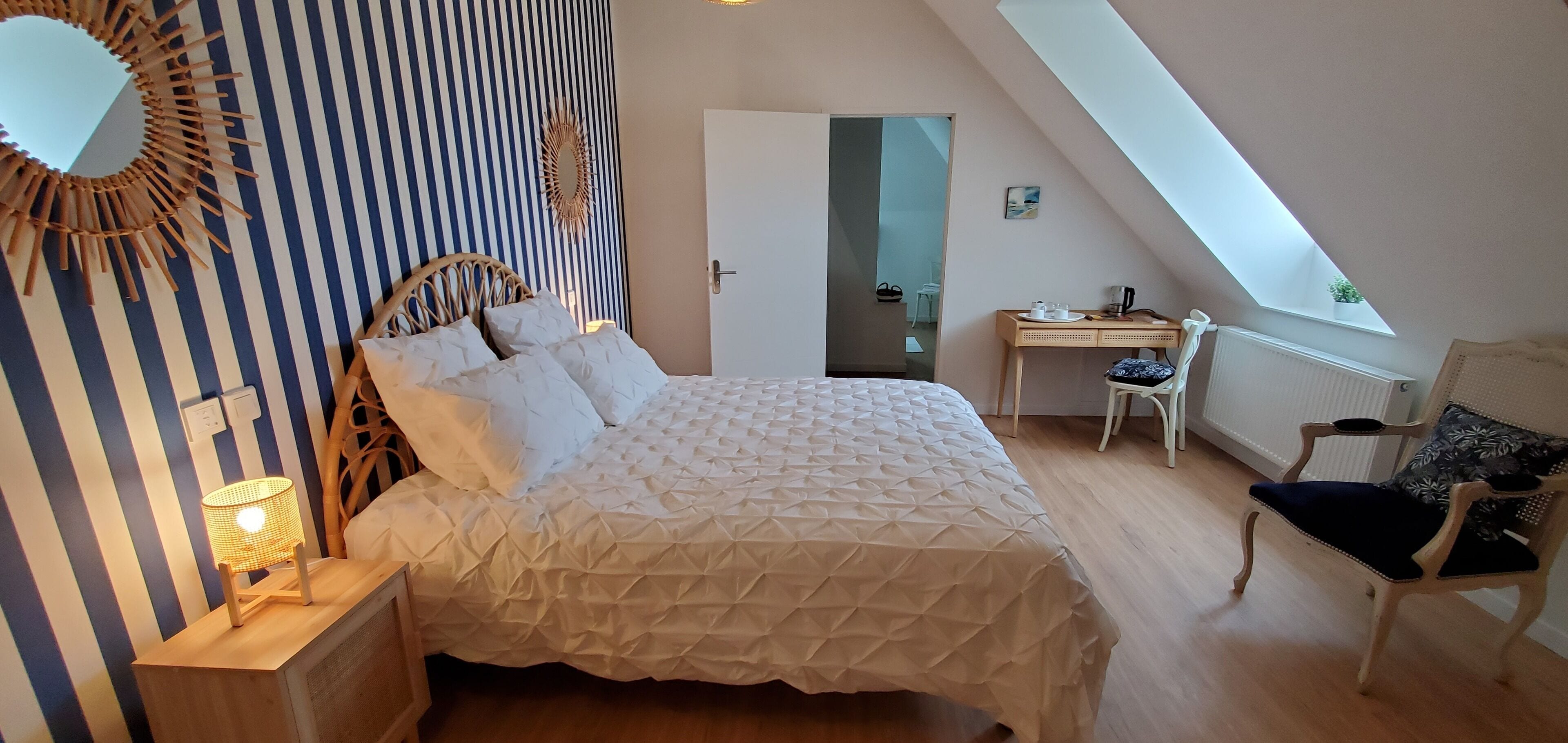 Een slaapkamer met een bed, bureau, stoel en raam.