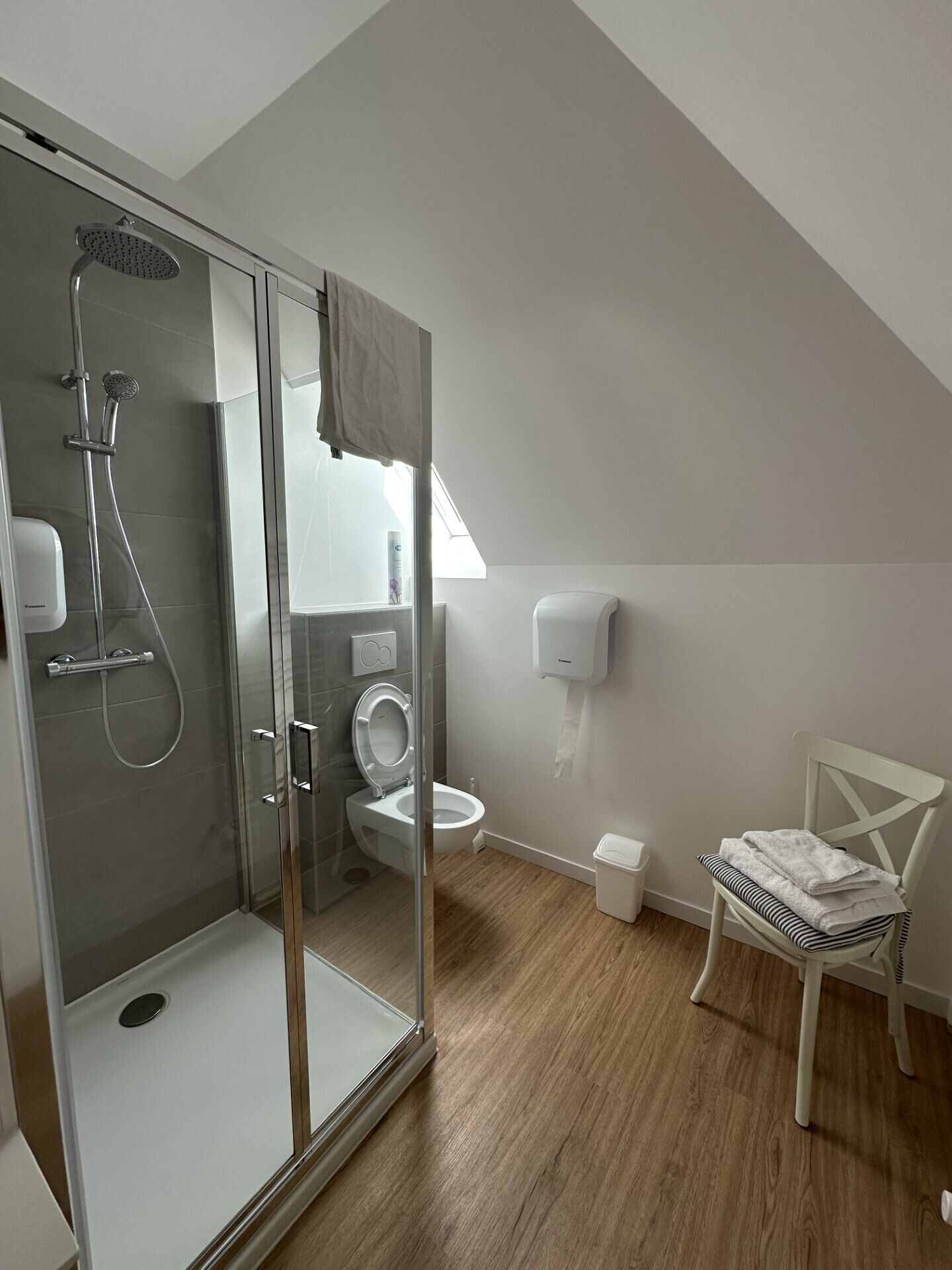 Et moderne badeværelse med en glasafskærmet brusekabine, toilet og håndvask.