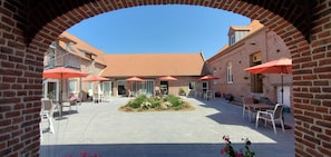 A courtyard with brick buildings, outdoor seating, and a central garden area.
