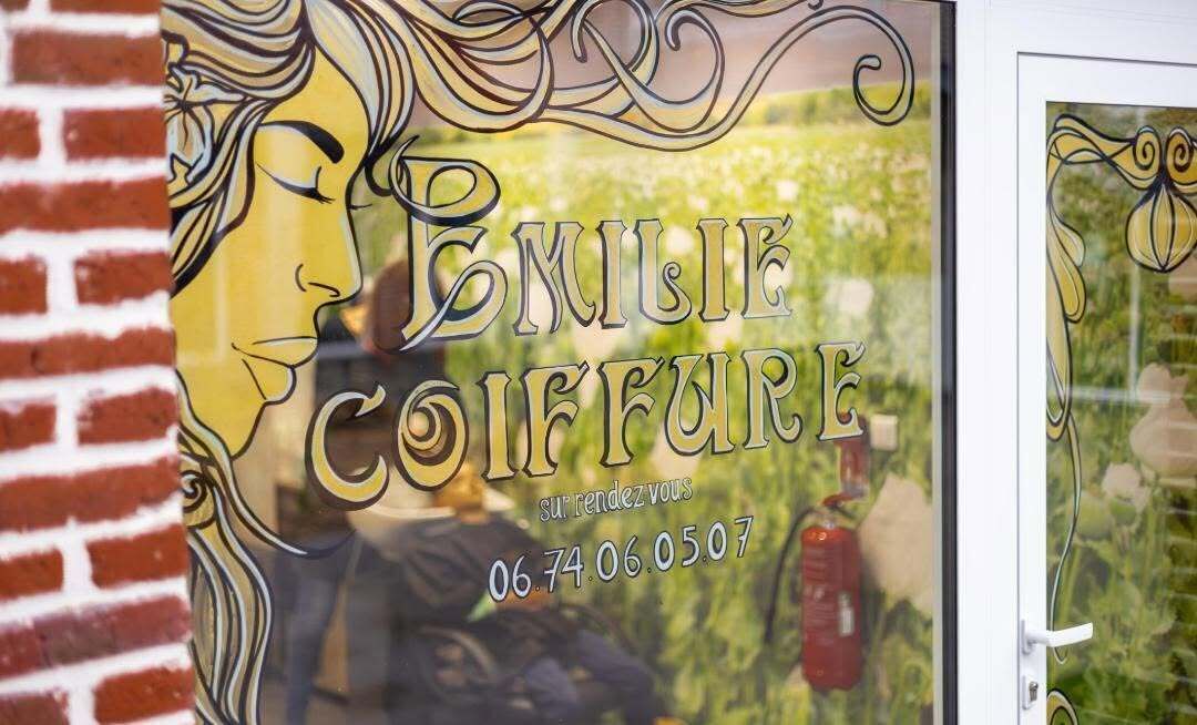 Una ventana con un diseño decorativo y el texto 'EMILE COIFFURE' junto con una fecha '06.74.06.05.07'.