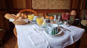 Una mesa para el desayuno dispuesta con pan, jugo, una taza y un plato.
