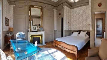 Ein Zimmer mit einem Bett, einem Schreibtisch, einem Stuhl, einem Kamin und einem großen Fenster.
