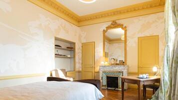 Een hotelkamer met een bed, een bureau, een open haard en een grote spiegel.