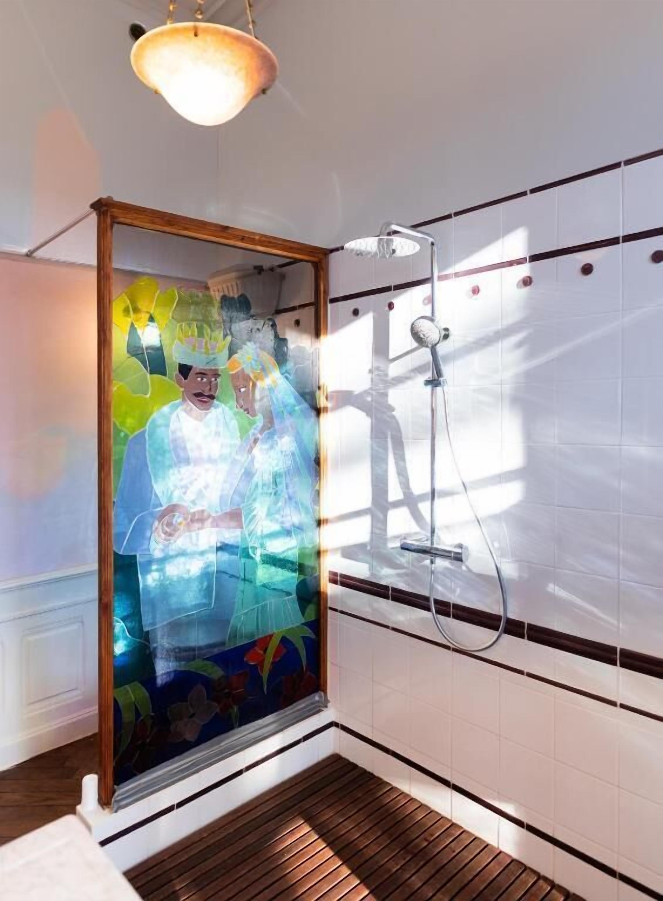 Een douche met een glazen deur, een houten vloer en een plafondlamp.
