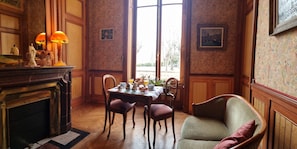 Una habitación con una mesa de comedor lista para el desayuno, una chimenea y vistas a través de un ventanal grande.