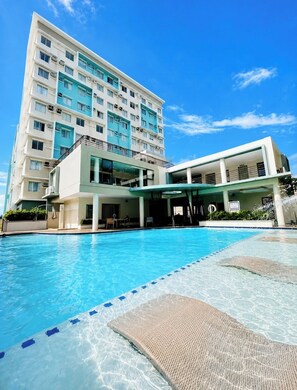 Ein Hotel mit Schwimmbad, überdachtem Bereich und einem mehrstöckigen Gebäude mit Balkonen.