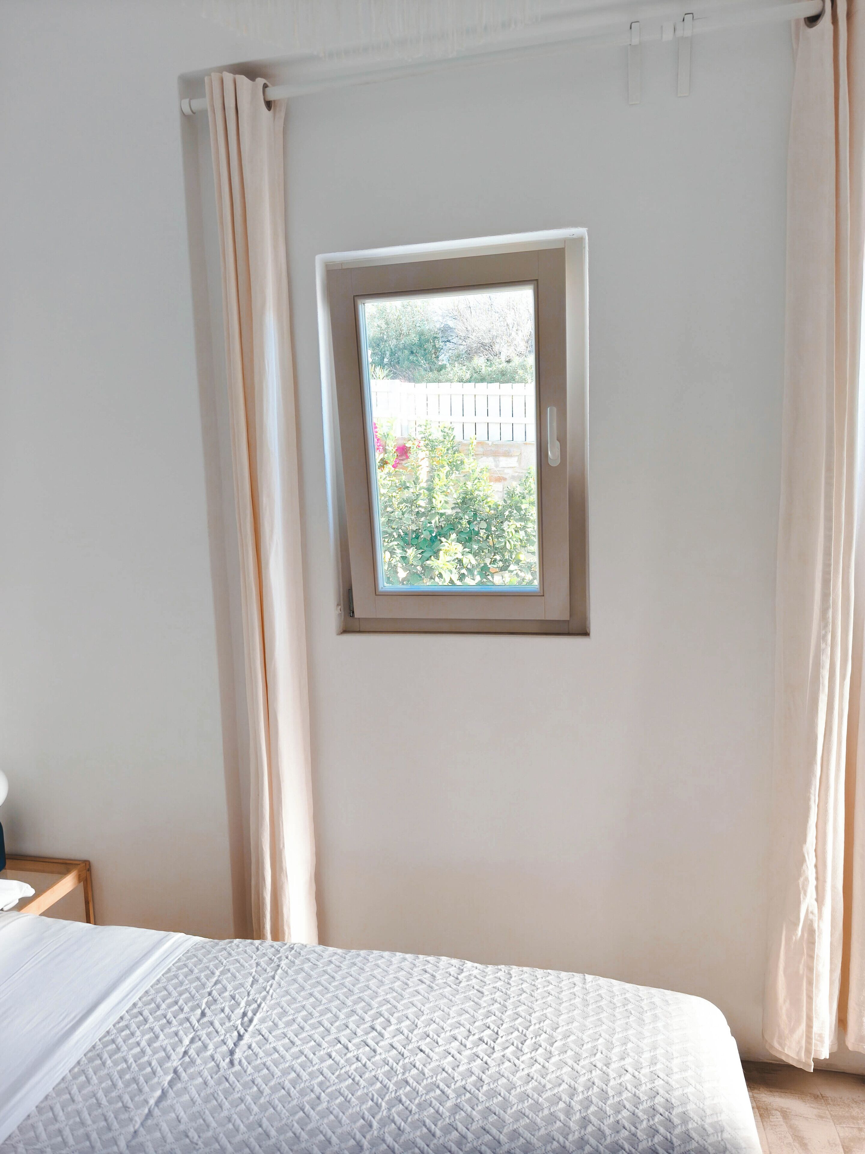 A bedroom with a bed, a window, and curtains.