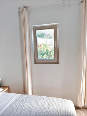 Un dormitori amb un llit, una finestra i cortines.