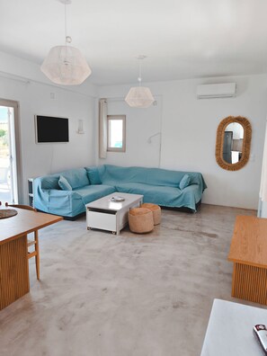 Un saló modern amb un sofà seccional, una taula de centre i una zona de menjador amb taula i cadires.
