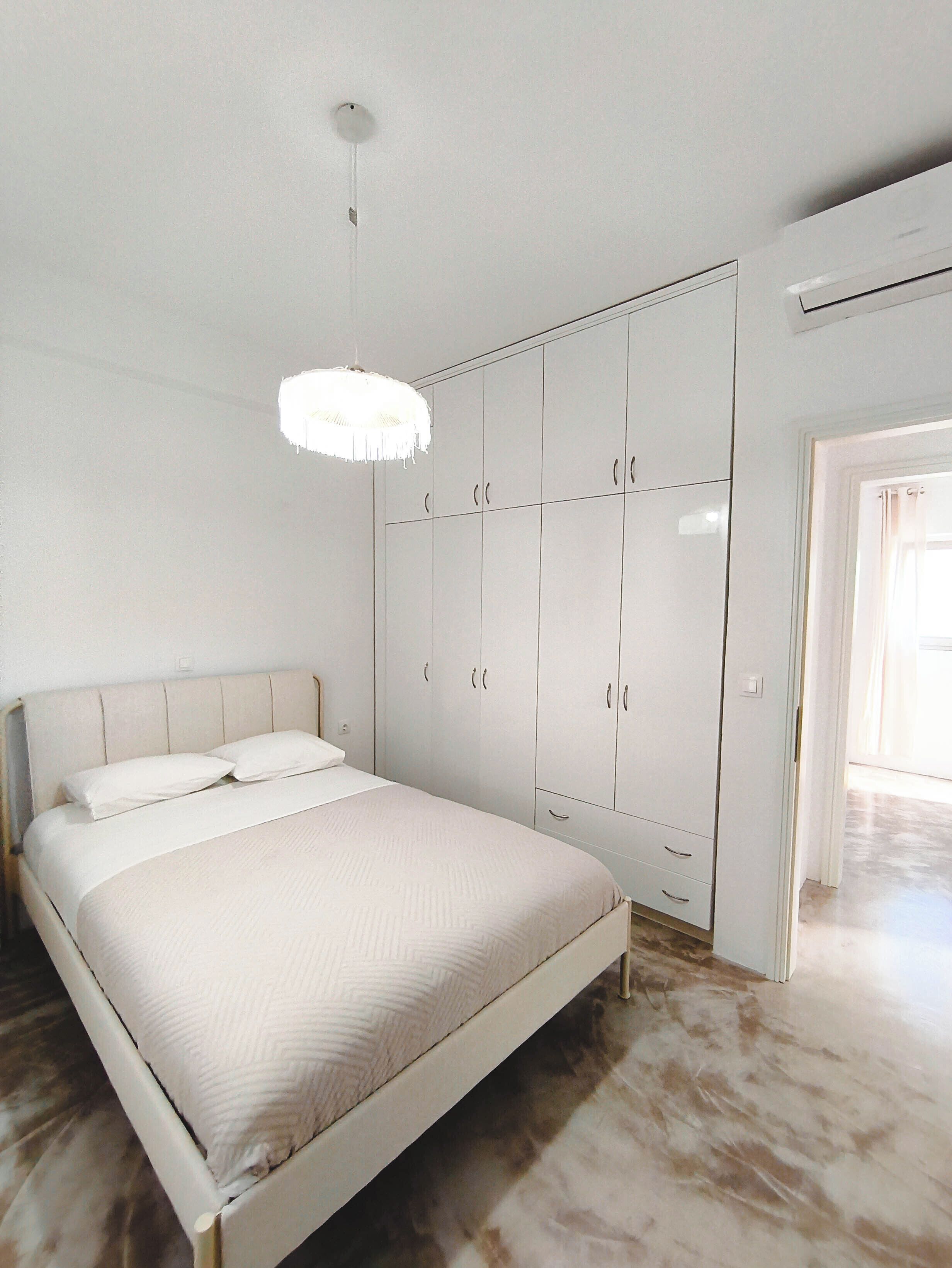 Une chambre à coucher avec un lit, une armoire et un luminaire suspendu.