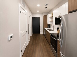 Eine moderne Küche mit einem Edelstahl-Kühlschrank, einer Mikrowelle und einem Spülbecken.